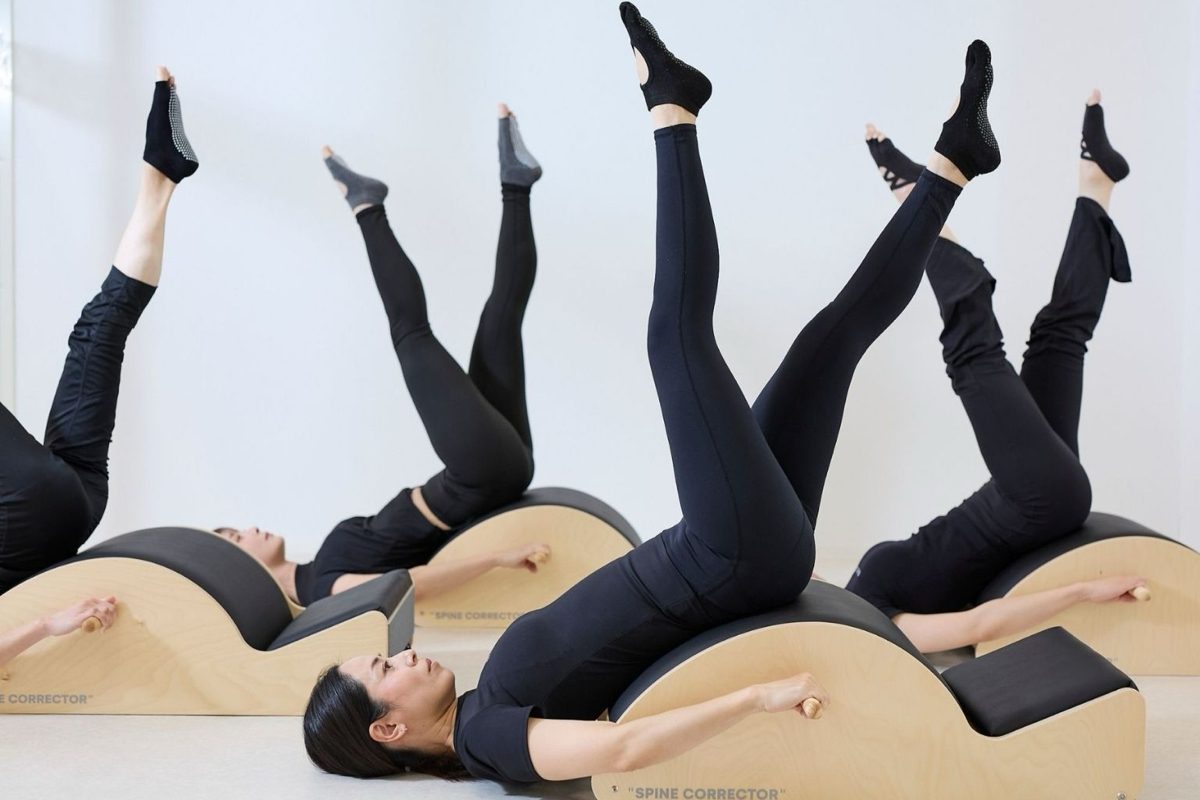 A group class at BLACK CAT: participants lying back over spine correctors with legs raised.