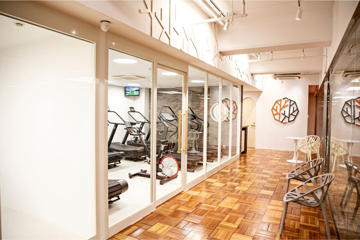 Interior of SOLERA: a glass-walled training room with treadmills, seen across a parquet floor.