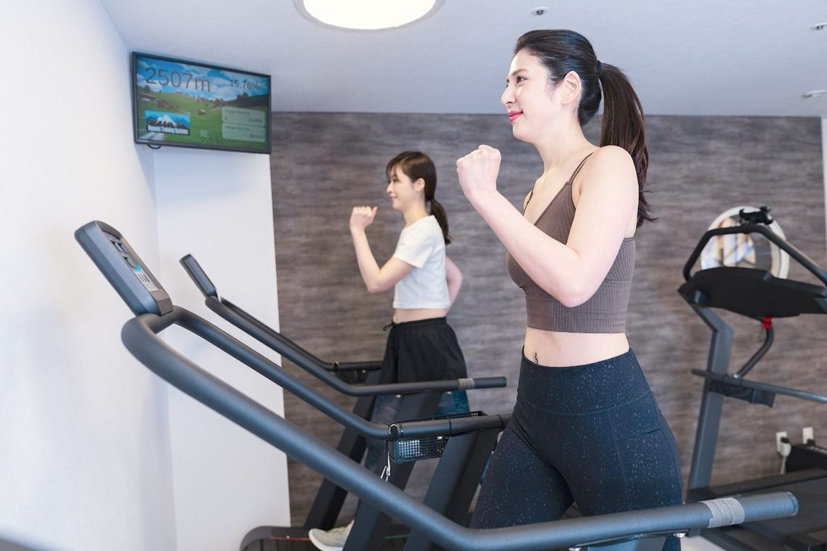 Two people walking on treadmills at SOLERA, with the simulated altitude shown on a wall monitor.