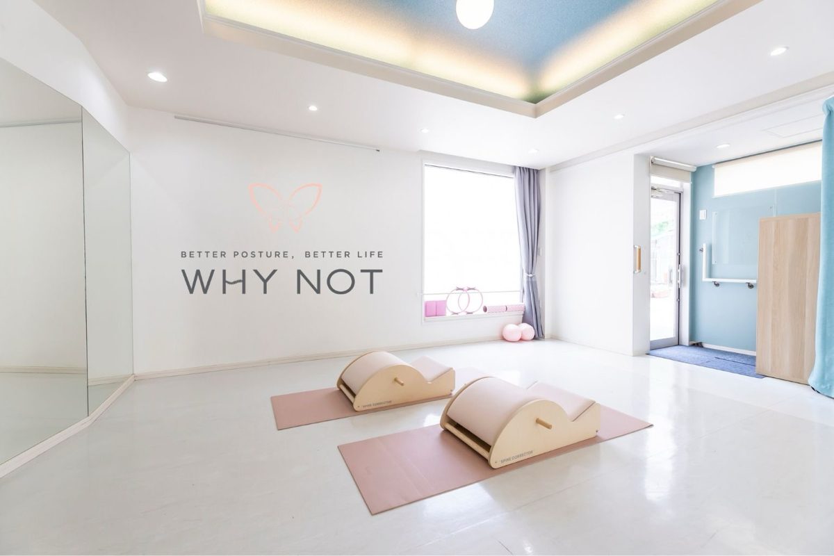 Interior of a WHY NOT studio: the brand logo on the wall, with two spine correctors on mats.